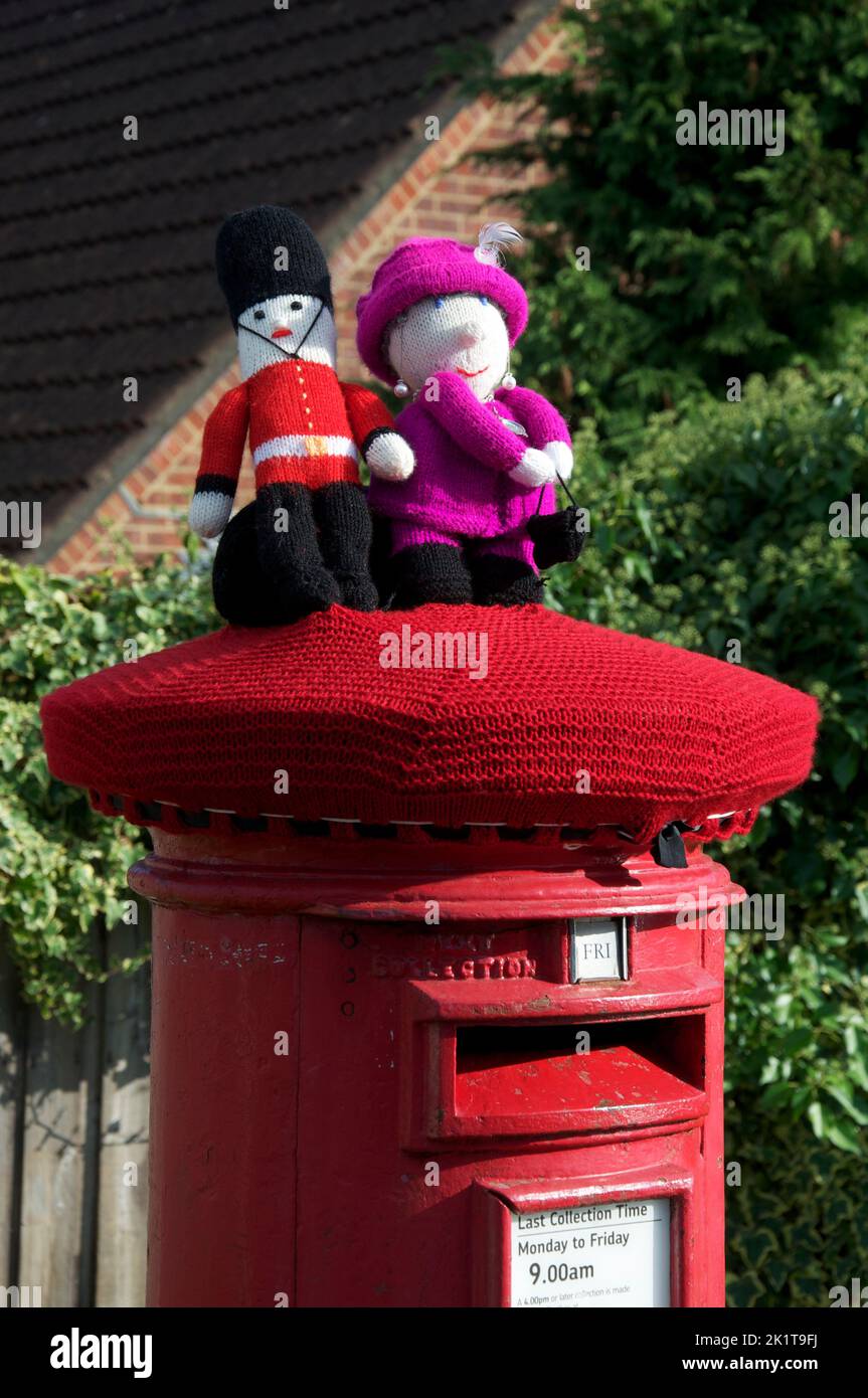 Quirky colourful handmade knitted woollen hat decorates a traditional red pillar box, celebrating the platinum Jubilee of Queen Elizabeth II. 2022, UK. Stock Photo