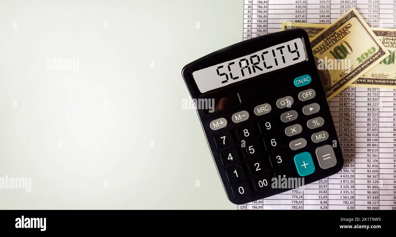 Calculator with SCARCITY text business concept, with dollar banknotes and documents on white background. Copy space Stock Photo