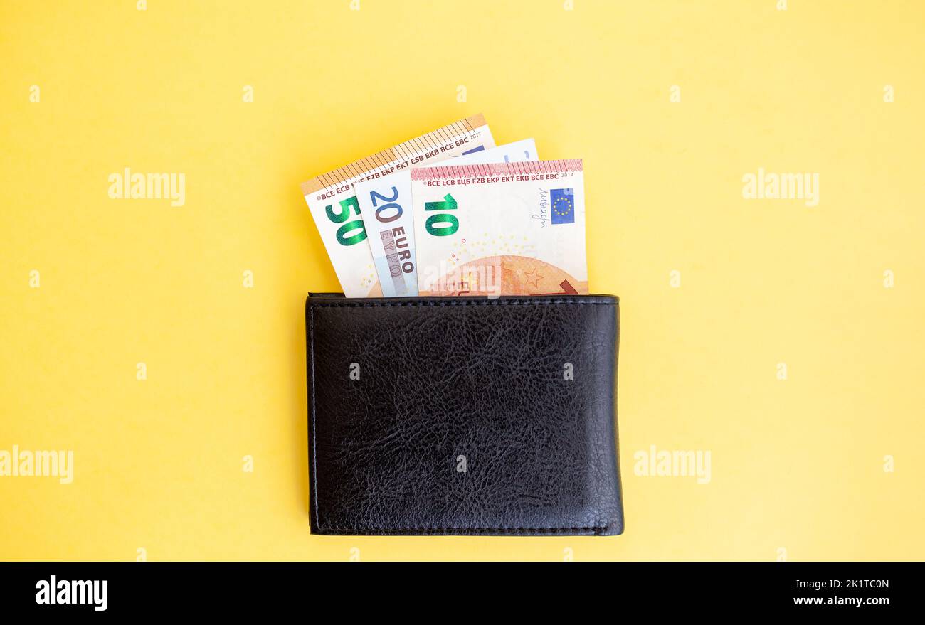 Different euro banknotes inside a black wallet on yellow background, cash paper currency, payment, earning and savings, european currency, money and f Stock Photo