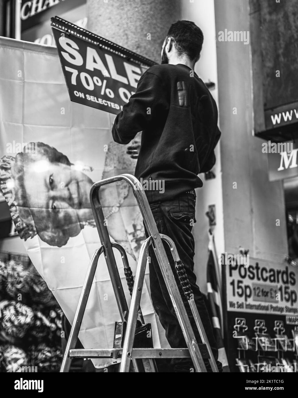 A sales person puts up a 70% discount sign on the Queen memorabilia in a store in central London. Stock Photo