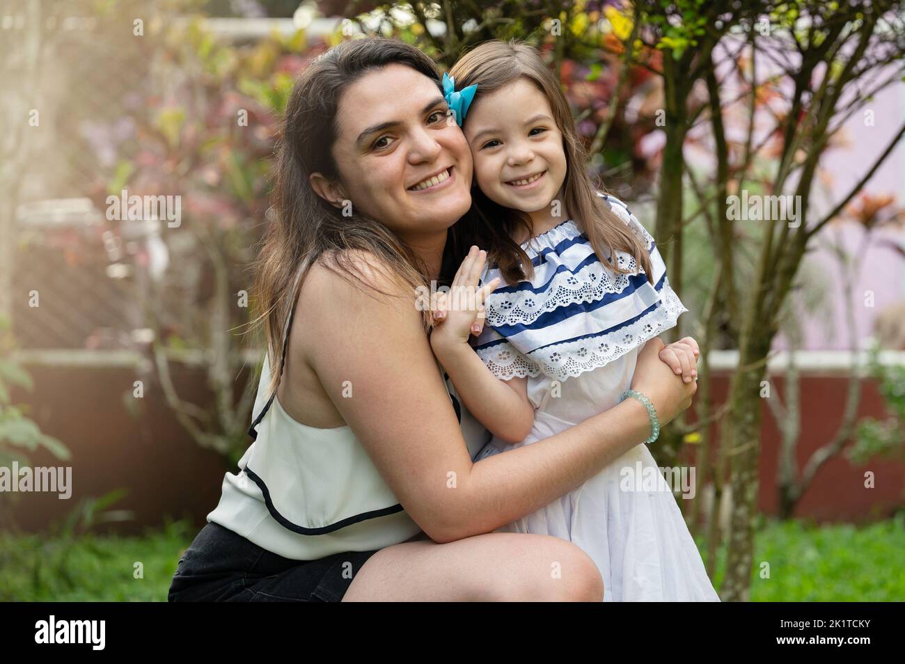Portrait of hispanic mother and daughter on blurred park background Stock Photo