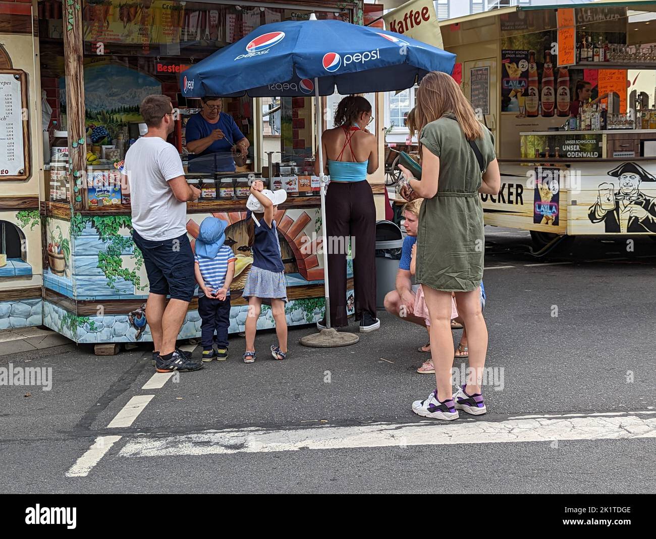 A group of people waiting in line at a crepes stand at a street fair Stock Photo
