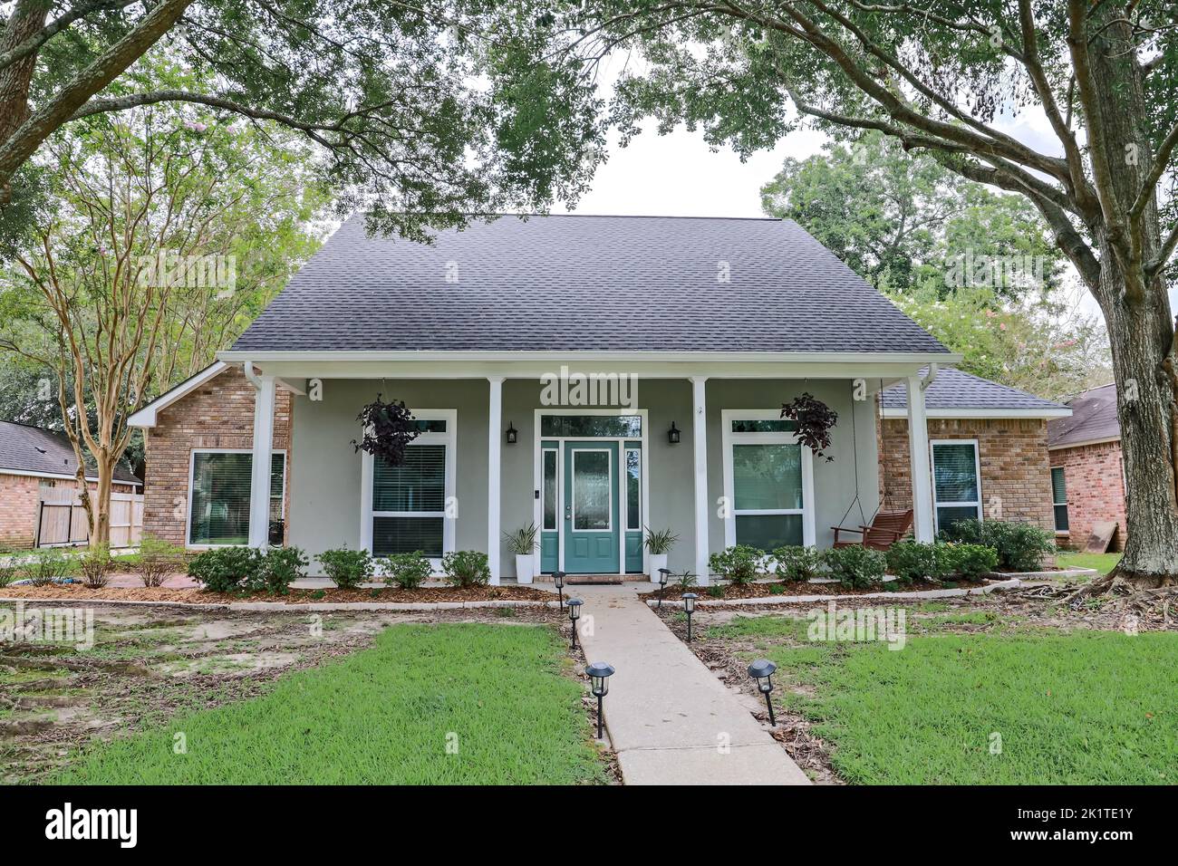 A front view of an Acadian renovated home with columns, sidewalks and a colorful front door recently purchased with the changing real estate market. Stock Photo