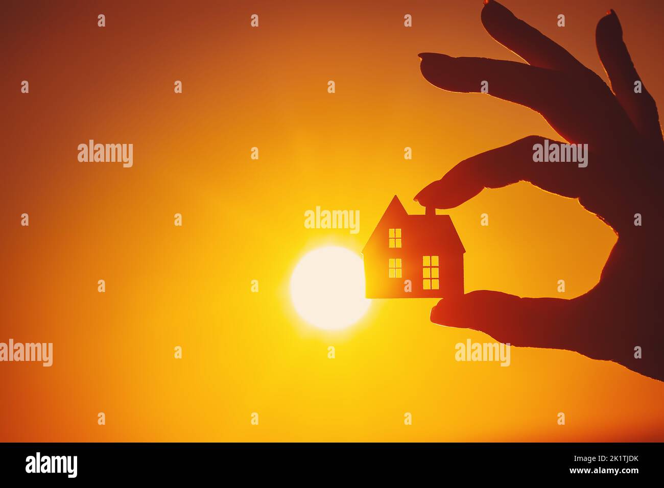 Woman's hand holding a model of a house on sunset evening Stock Photo