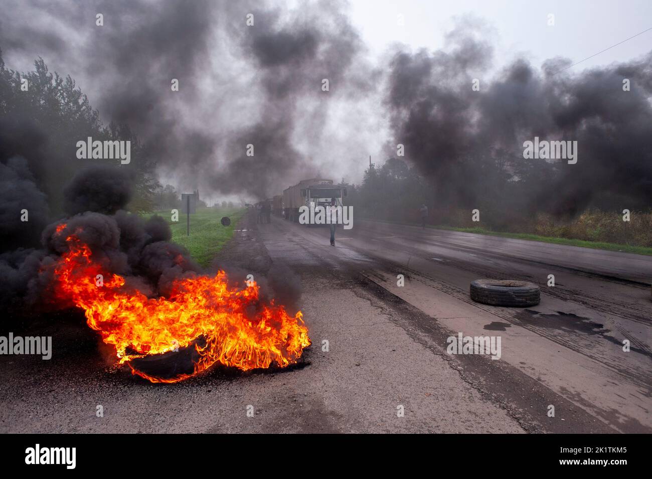 The workers burn tires in front of a factory during a protest in Firmat Stock Photo