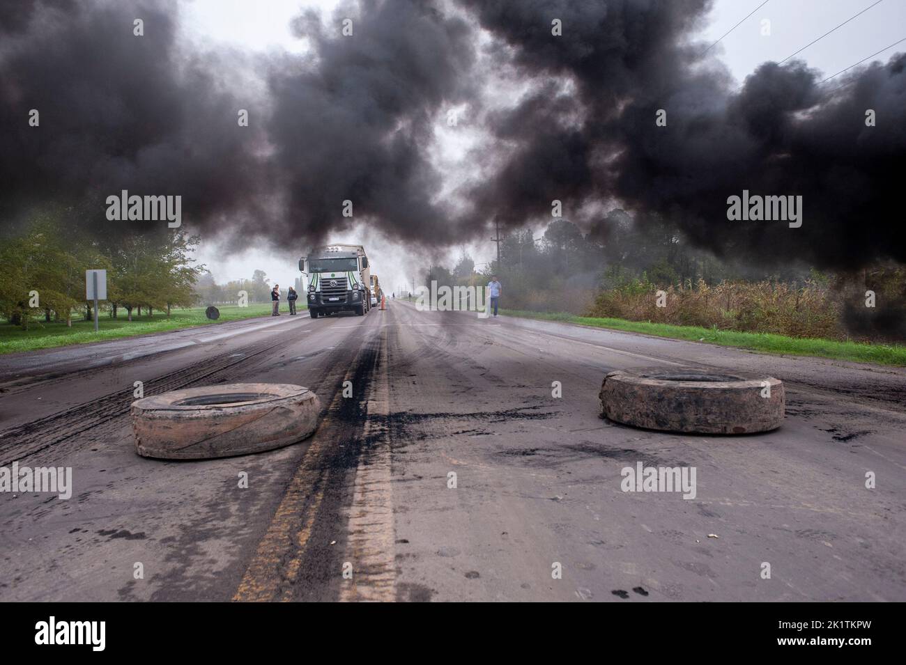 The workers burn tires in front of a factory during a protest in Firmat Stock Photo