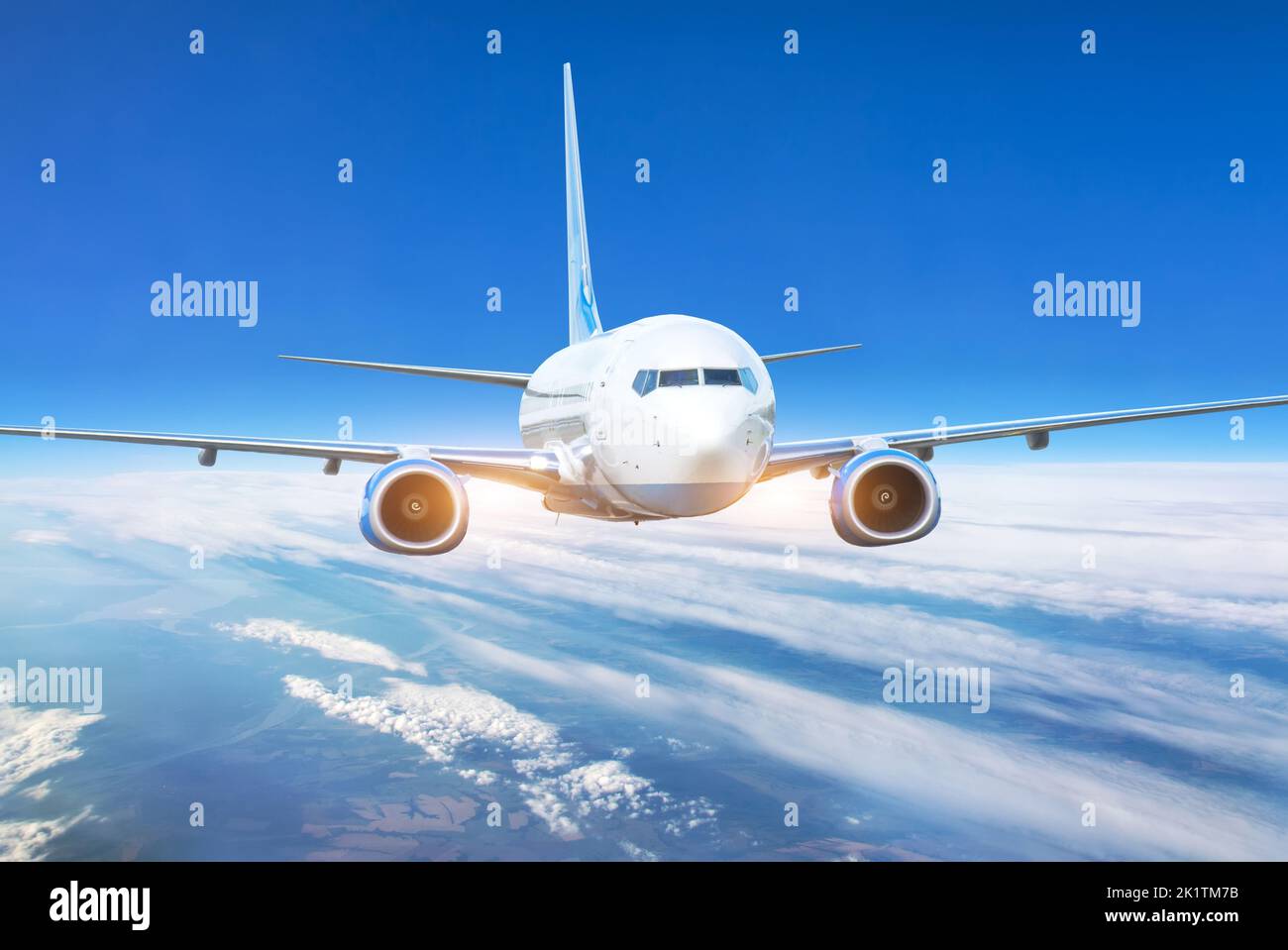 Passenger jet plane in the blue sky. Aircraft flying high through the cumulus clouds. Close up view airplane in flight. Stock Photo