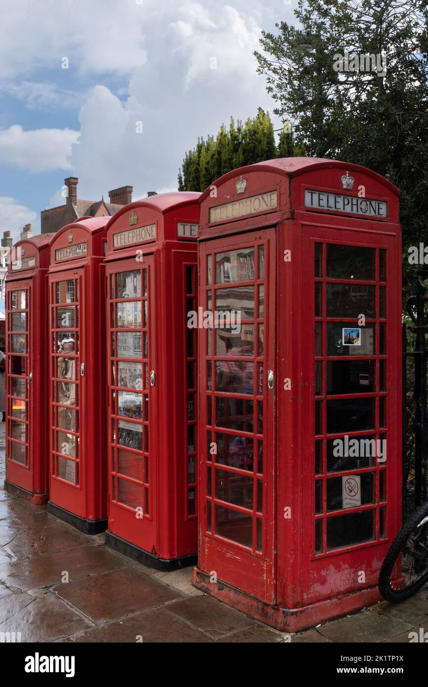 Three typical red English telephone boxes side by side on a wet Saint Mary's Street in Cambridge, UK Stock Photo
