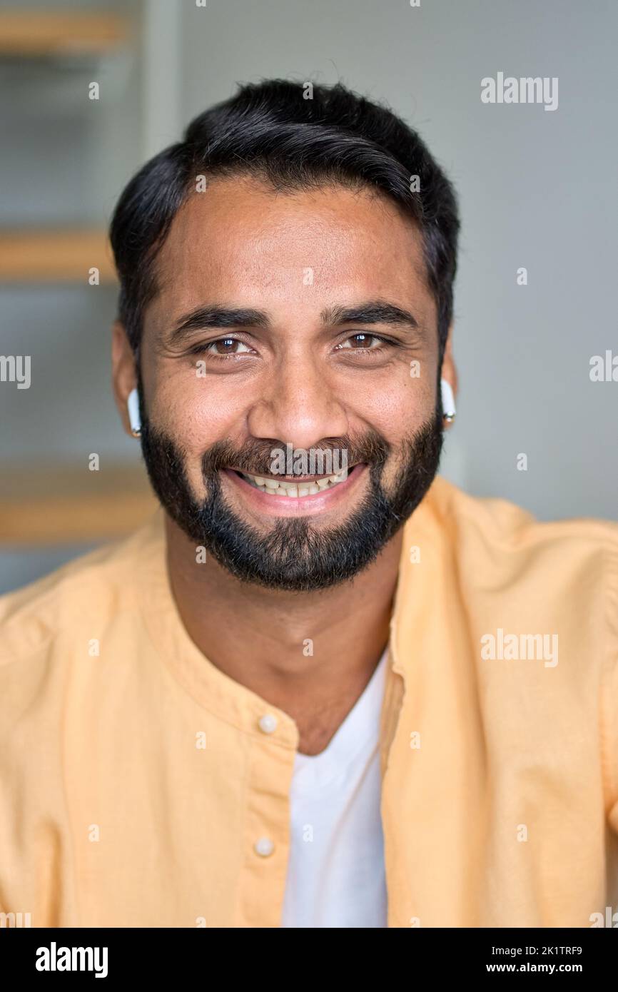 Happy smiling indian man looking at camera indoors. Close up vertical portrait. Stock Photo