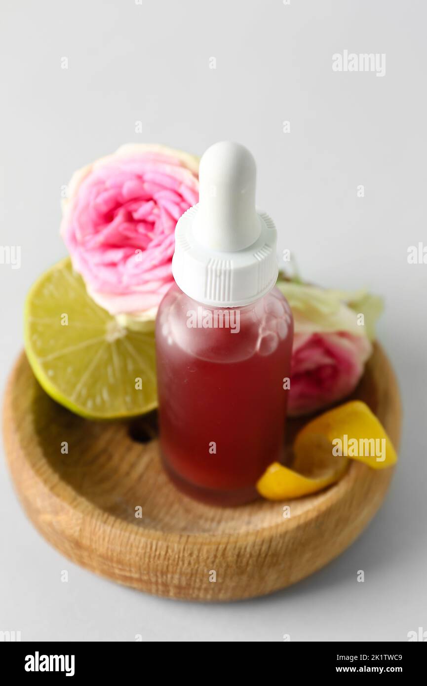 Wooden bowl with bottle of citrus serum on grey background, closeup ...