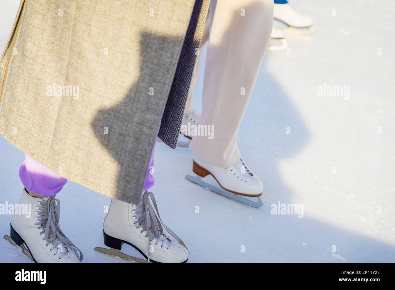 Skating rink in park, legs with skates of two girls. Winter outdoor sport concept. Selective focus Stock Photo