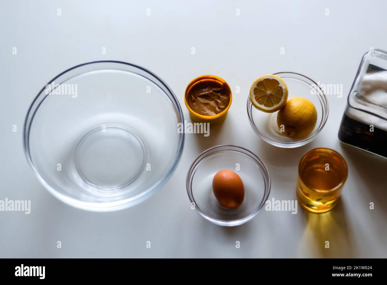 Defocus homemade mayonnaise sauce and olive oil, eggs, mustard, lemon, glass bowl. Top view of ingredients for homemade mayonnaise as mustard, eggs, s Stock Photo