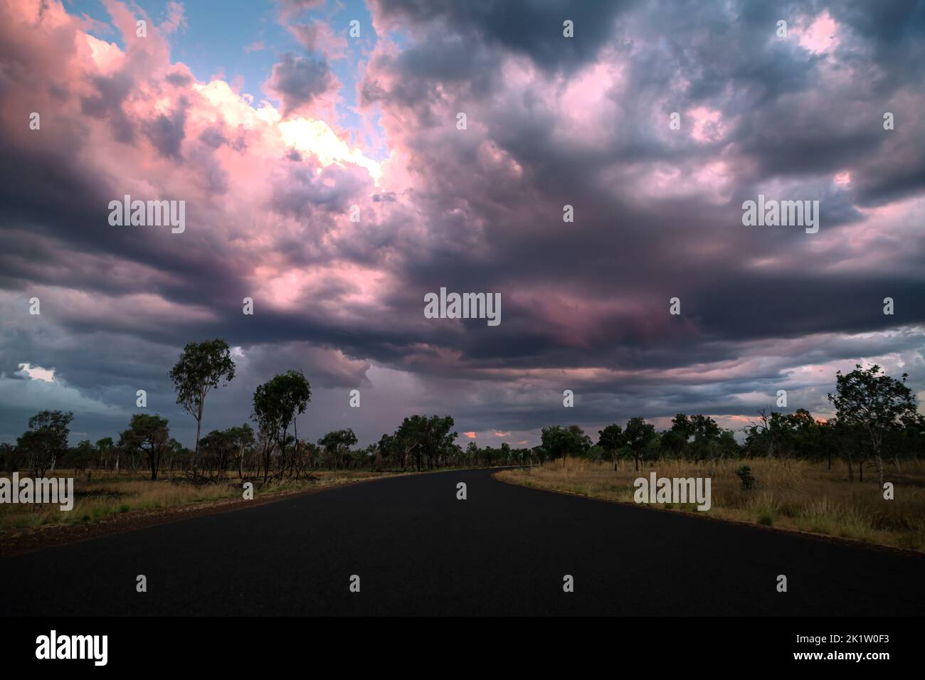 Road in wet season in the tropical north of Australia comes with thunderstorms and dark, dramatic clouds Stock Photo