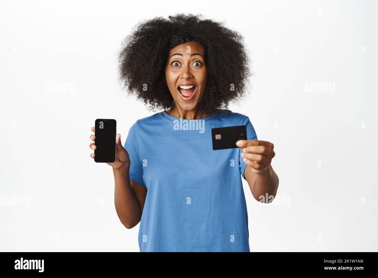Enthusiastic Black woman demonstrating her mobile phone screen and credit card, showing announcement in app, recommending bank or shopping application Stock Photo