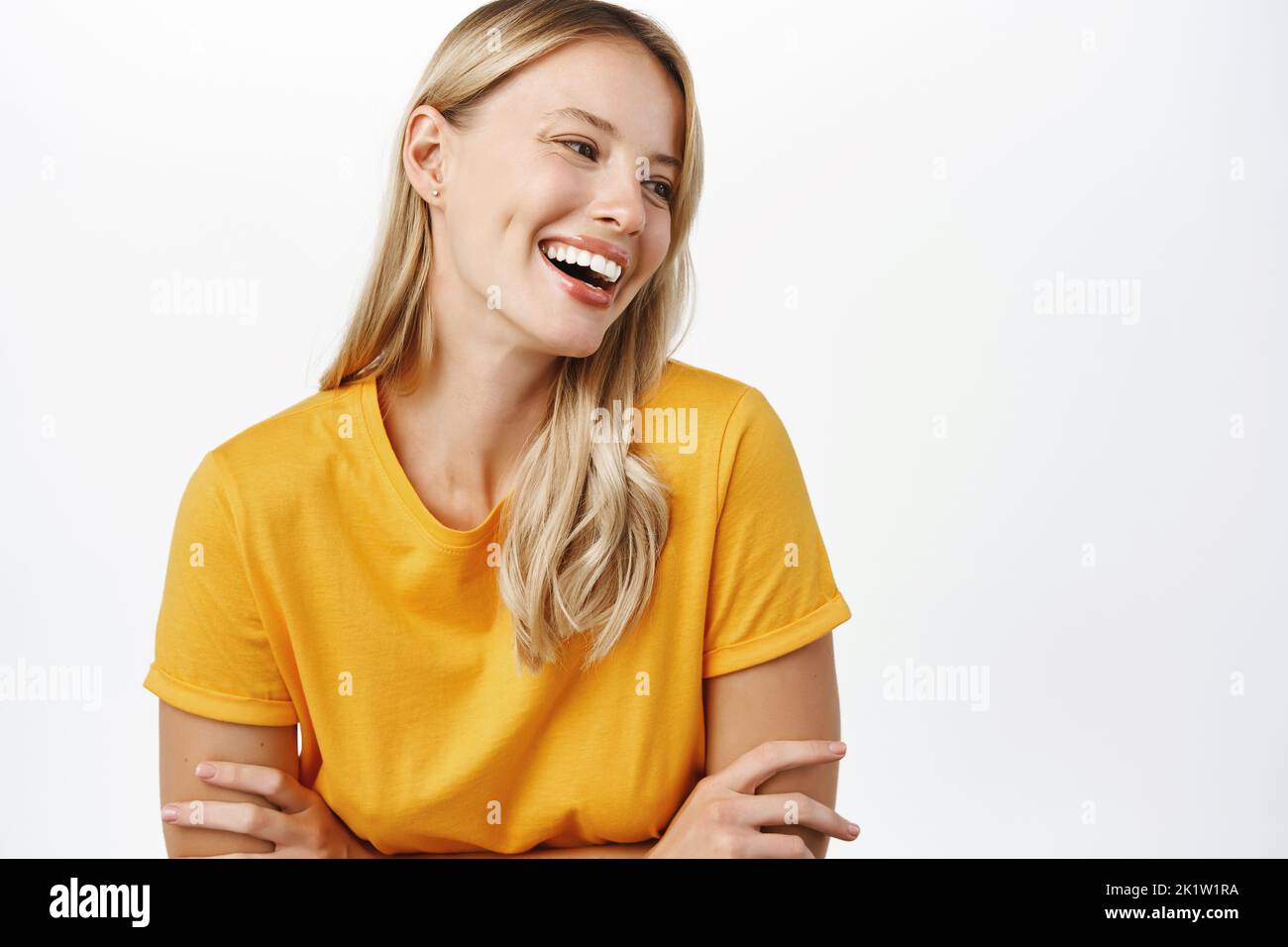 Portrit of beautiful modern woman with natural blond hair, white smile, clear perfect skin, laughing and smiling, standing in yellow t-shirt over whit Stock Photo