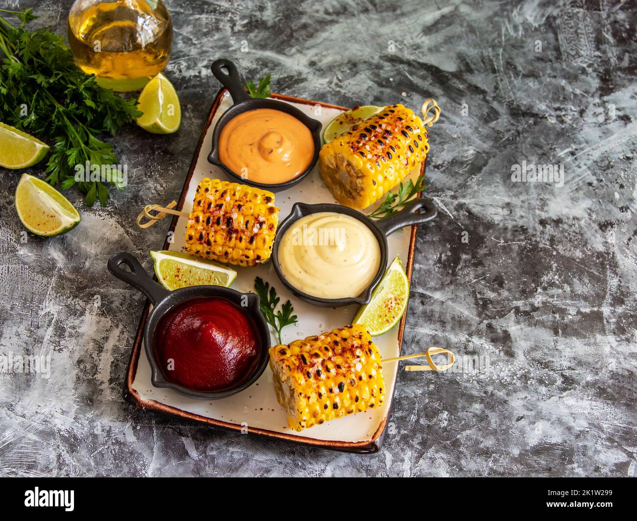 grilled yellow head corn with spices lime with white red orange sauce portion Stock Photo