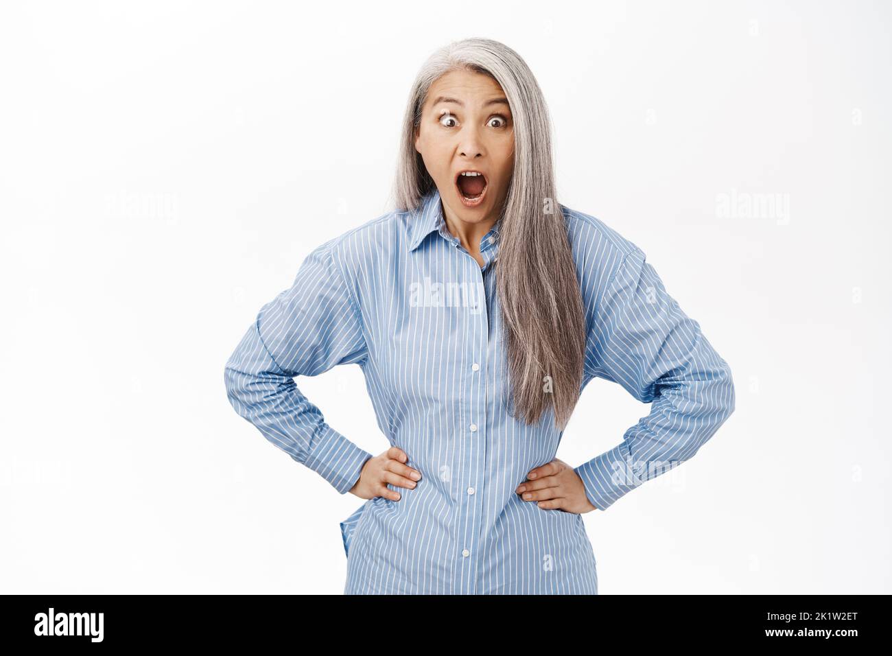 Impressed asian lady saying wow, looking amazed by smth, standing over white background. Stock Photo