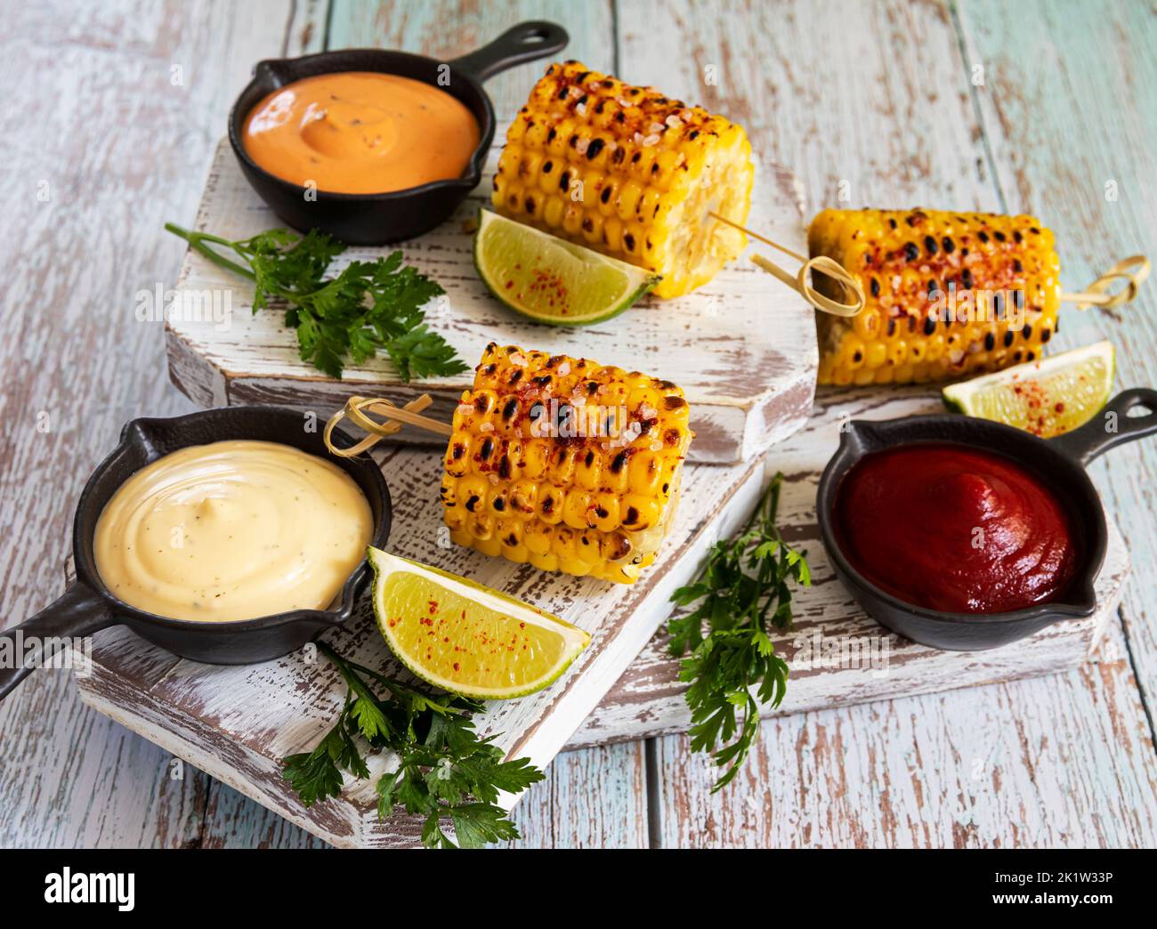 grilled yellow head corn with spices lime with white red orange sauce portion Stock Photo