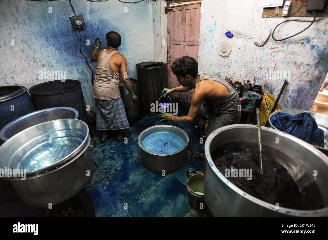 07.12.2011, Mumbai, Maharashtra, India, Asia - Workers dye fabrics in a metal vat at a workshop in the Dharavi slum area of Mumbai. Stock Photo