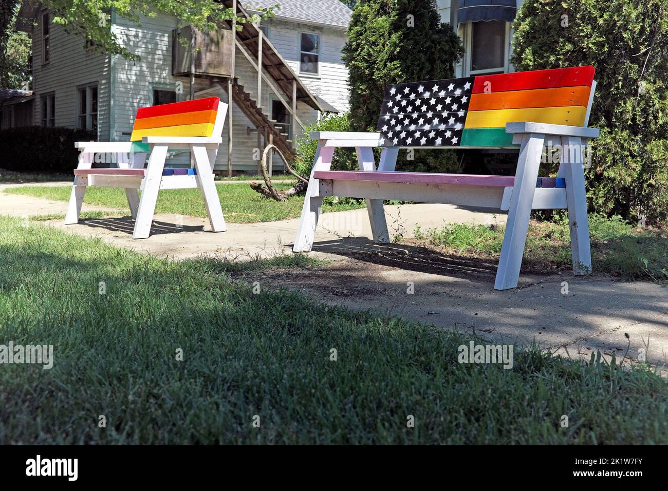 Two rainbow painted benches sit empty on a sidewalk in the LGBTQ friendly town of Douglas, Michigan. Stock Photo