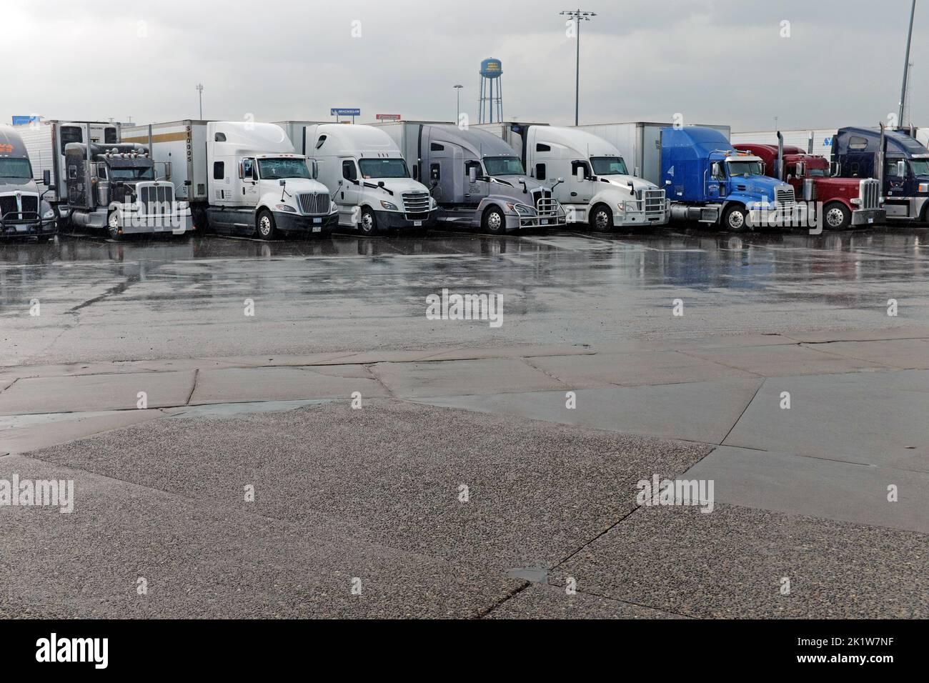 A row of semi trucks parked during a rain storm at the World's Largest Truck Stop, Iowa 80, in Walcott, Iowa, USA. Stock Photo
