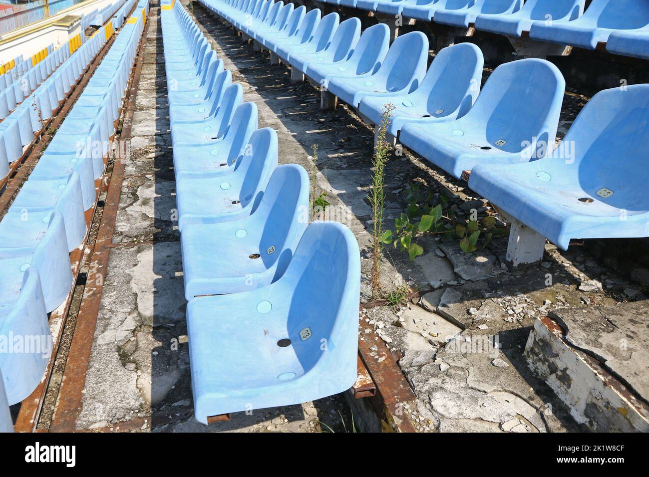 Details of football soccer stadium tribunes. Ruined steps, old blue seats Stock Photo