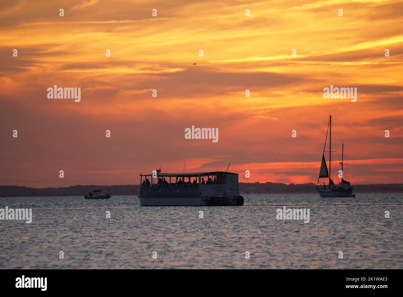 Lewes, Delaware, U.S.A - September 9, 2022 - Ferry and yacht overlooking the sunset near Cape Henlopen State Park Stock Photo
