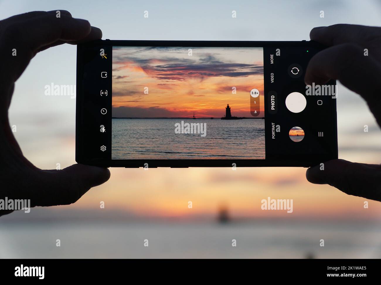 Lewes, Delaware, U.S.A - September 9, 2022 - Capturing sunset using a smartphone near Cape Henlopen State Park Stock Photo