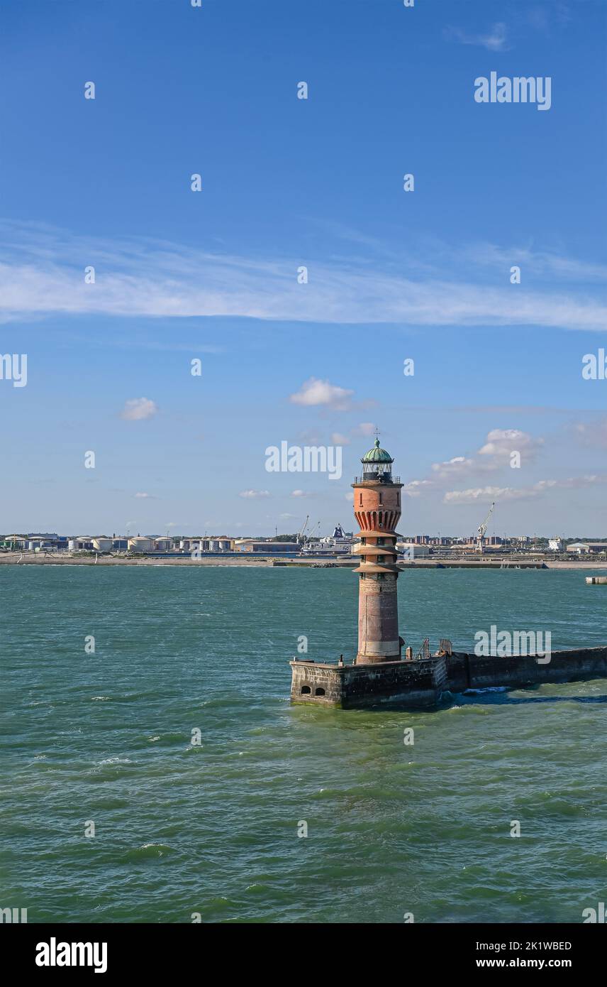 Europe, France, Dunkerque - July 9, 2022: Feu de Saint Pol light tower at entrance to port under blue sky. Huge petrol tanks at Freycinet Quay. Azure Stock Photo
