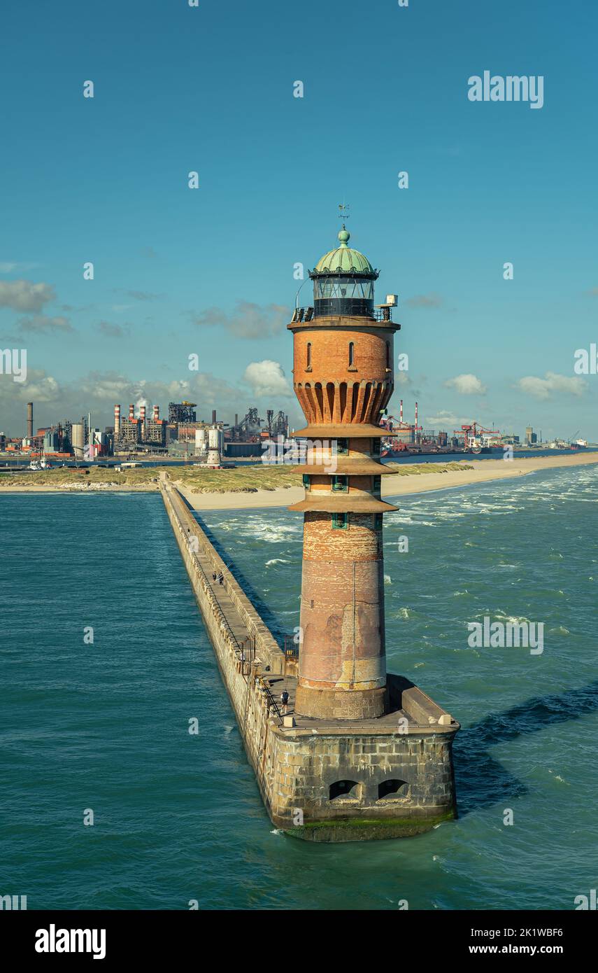 Europe, France, Dunkerque - July 9, 2022: Closeup, Feu de Saint Pol light tower on its pier at entrance to port under blue sky. Power generation facil Stock Photo