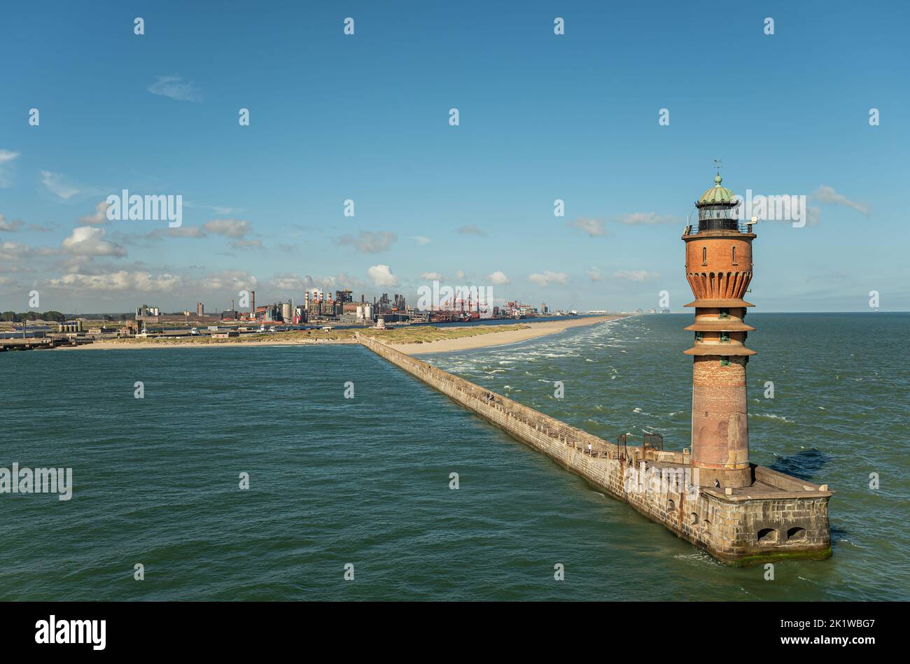 Europe, France, Dunkerque - July 9, 2022: Landscape, Feu de Saint Pol light tower on its pier at entrance to port under blue sky. Power generation fac Stock Photo