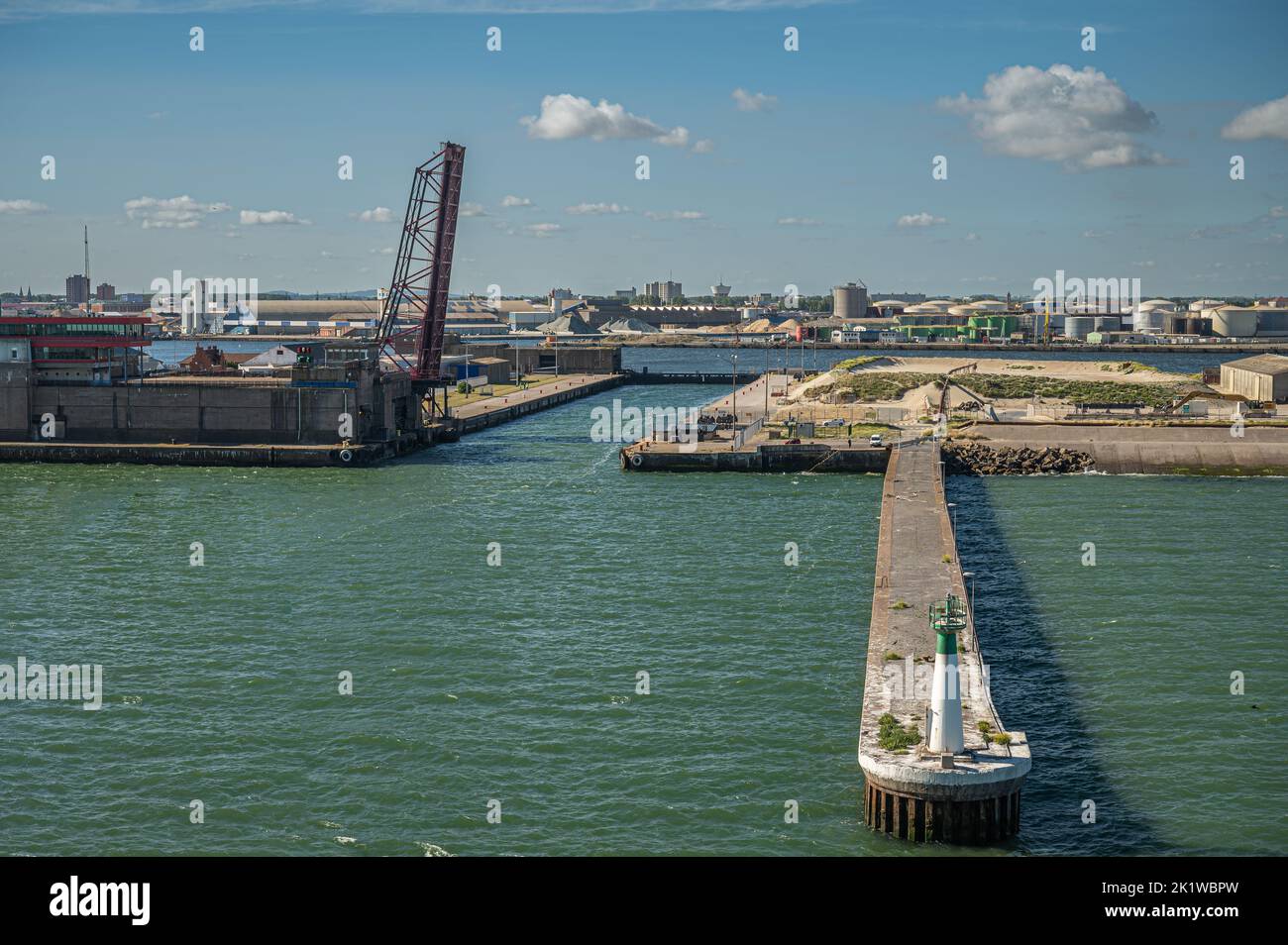 Europe, France, Dunkerque - July 9, 2022: Canal de Bourbourg lock, main entrance to port with its own pier and light tower under blue cloudcape. Verti Stock Photo