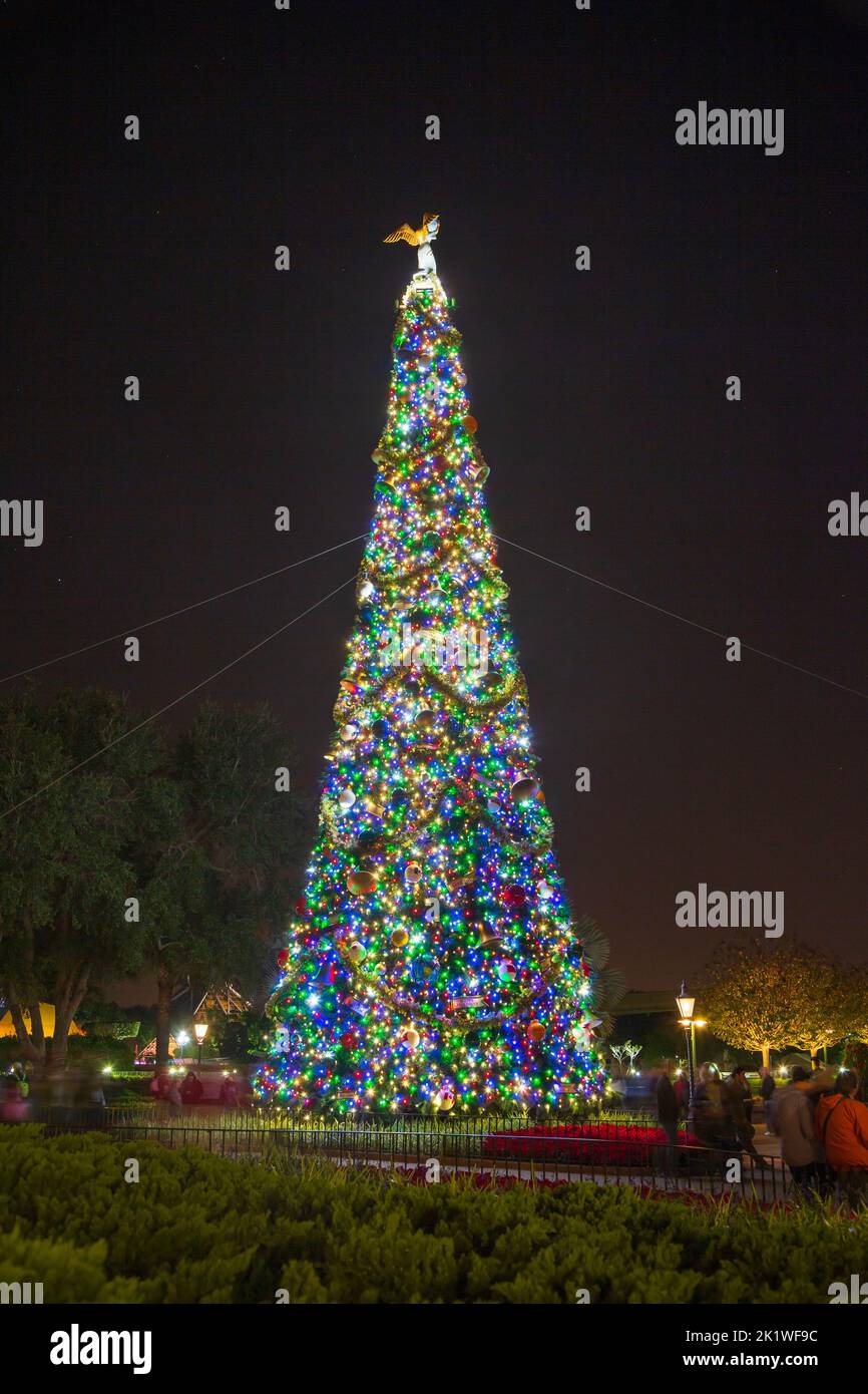 A tall Christmas tree illuminated at night and decorated at Epcot