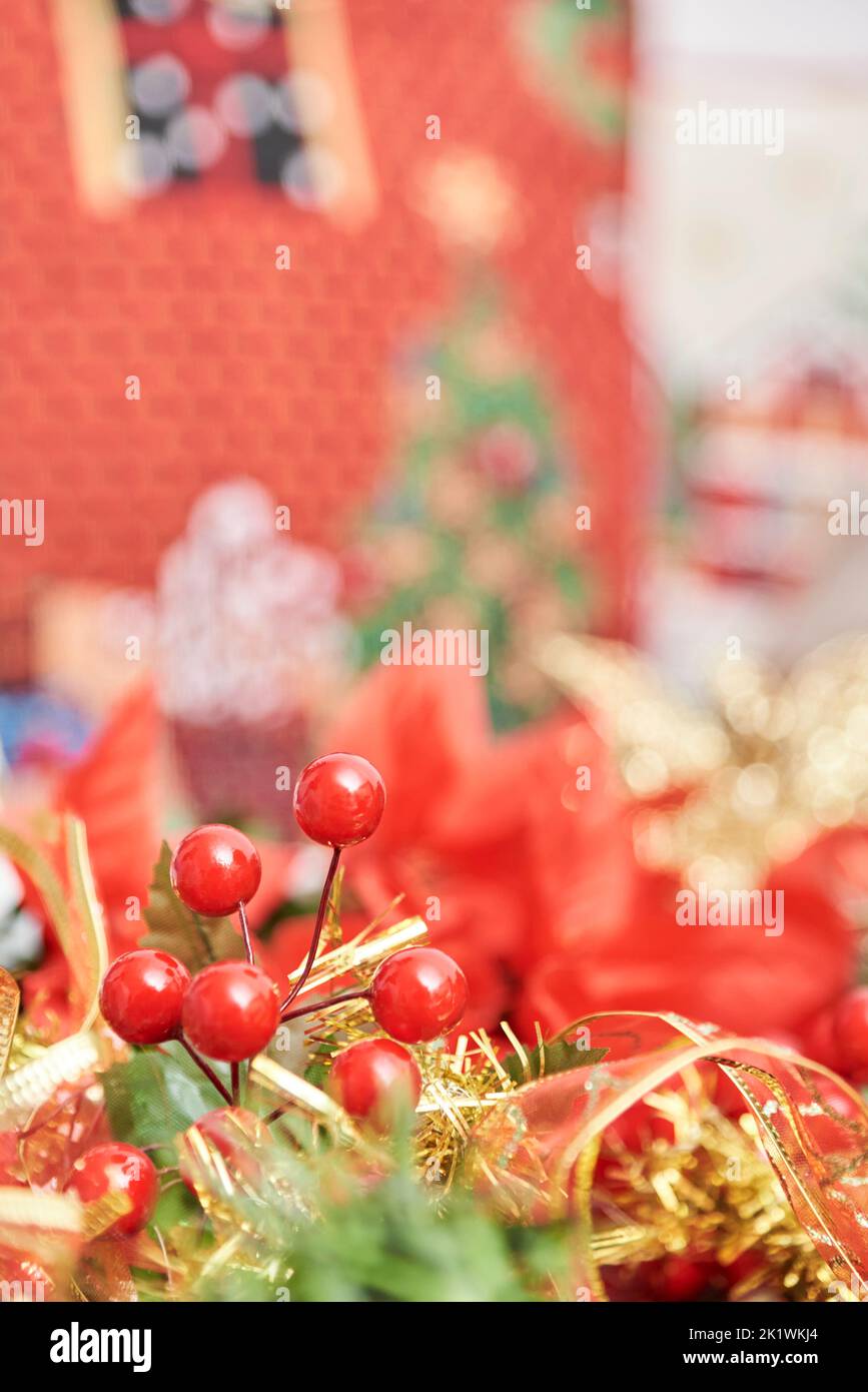Traditional Christmas theme background with red, green and gold. Red berries, ribbons and leaves in foreground. Composition with selective focus and c Stock Photo