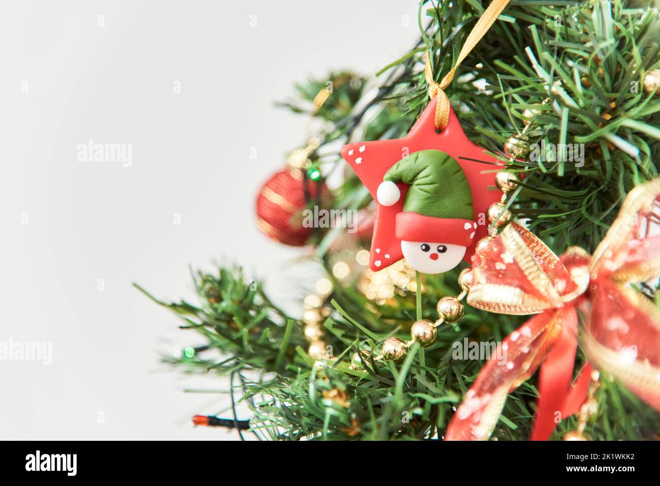 Close-up view of a Christmas tree with ornaments in traditional colors, red, green and gold. Composition with selective focus and copy space. Stock Photo