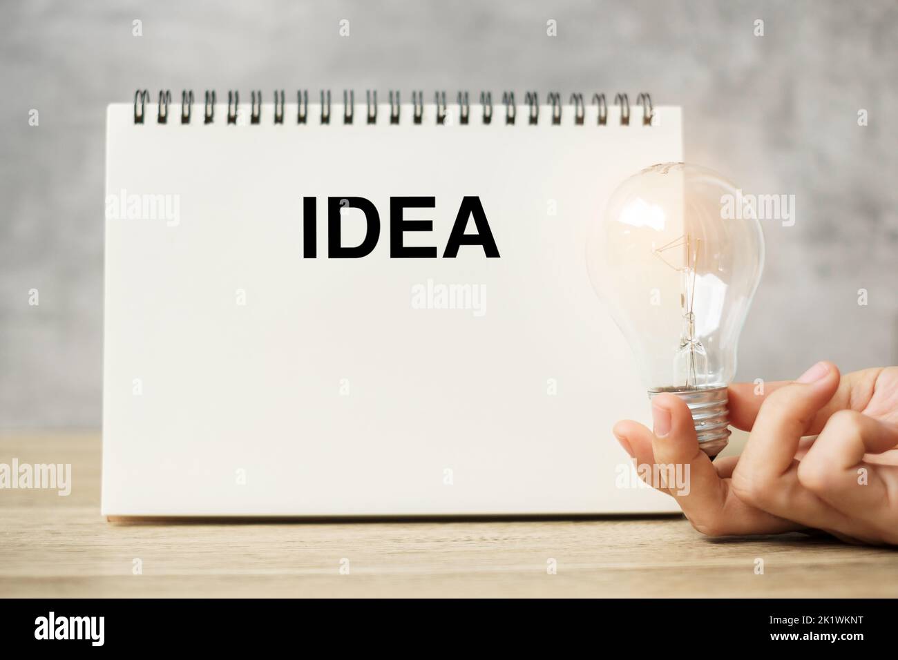 Hand holding lightbulb over notebook on table. New Ideas, Creative, Innovation, Imagination