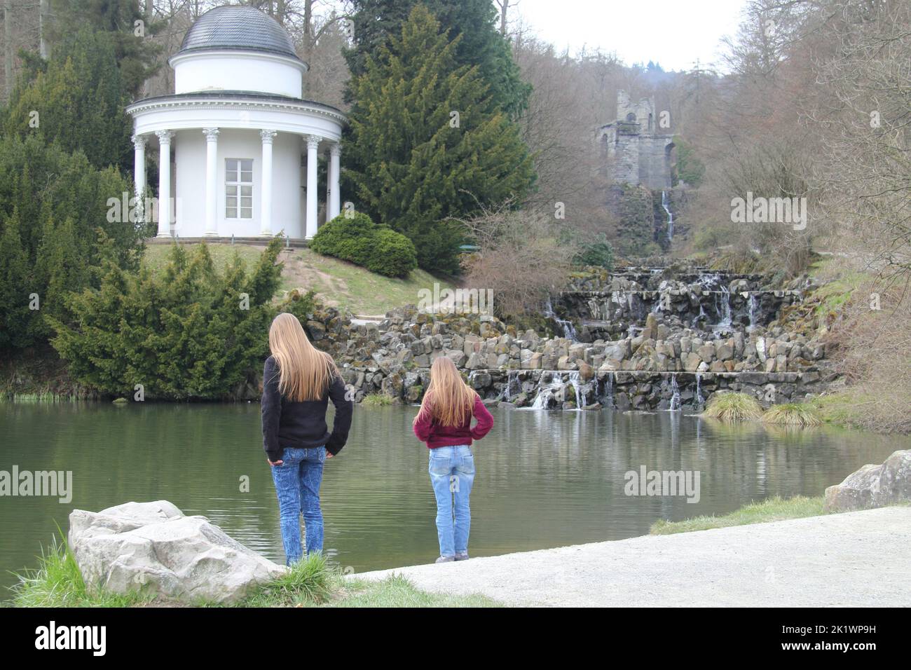 two blonde girl standing on the shore of a lake Stock Photo