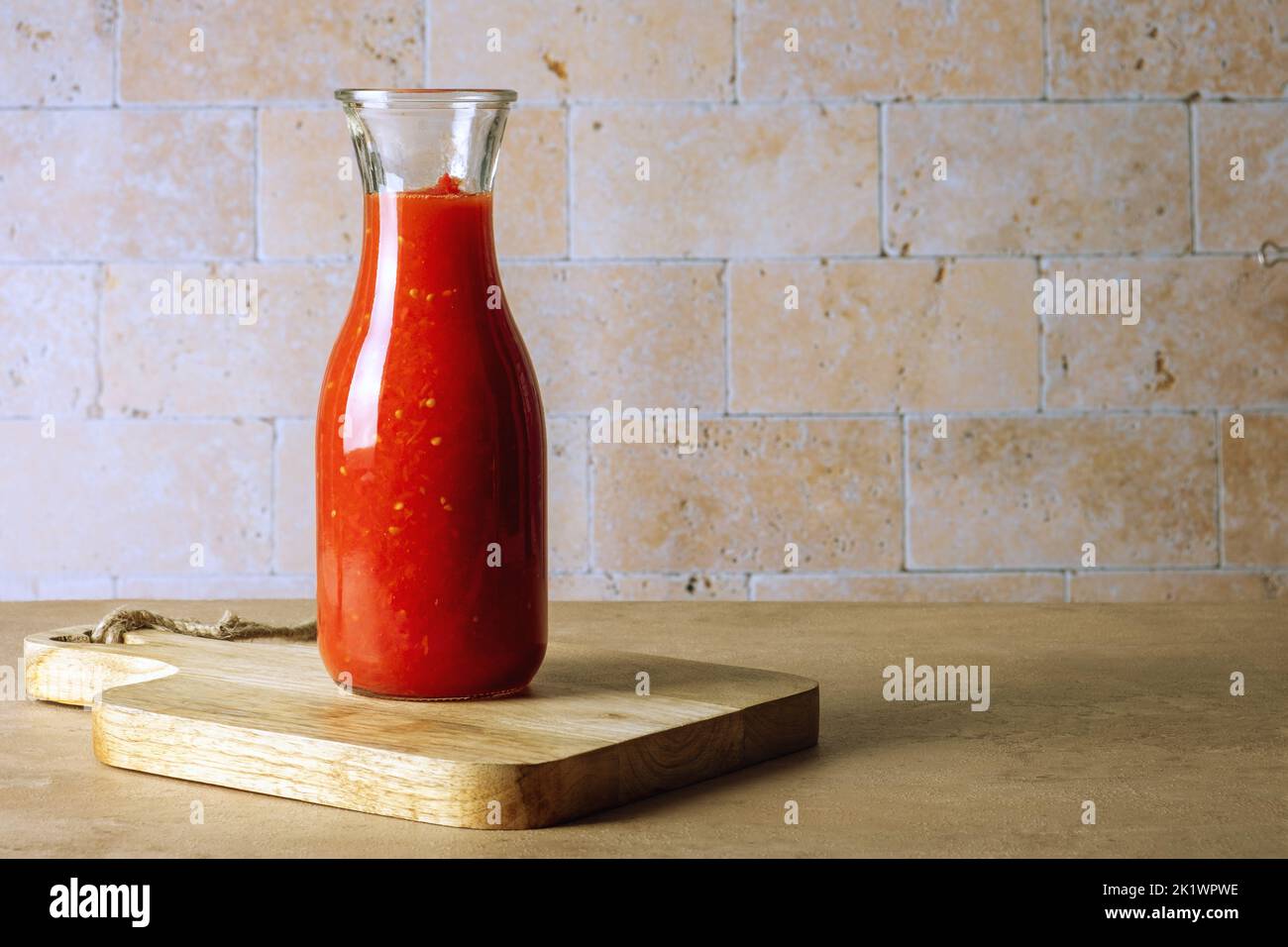 Glass jar bottle with homemade tomato sauce stands on cutting board Stock Photo