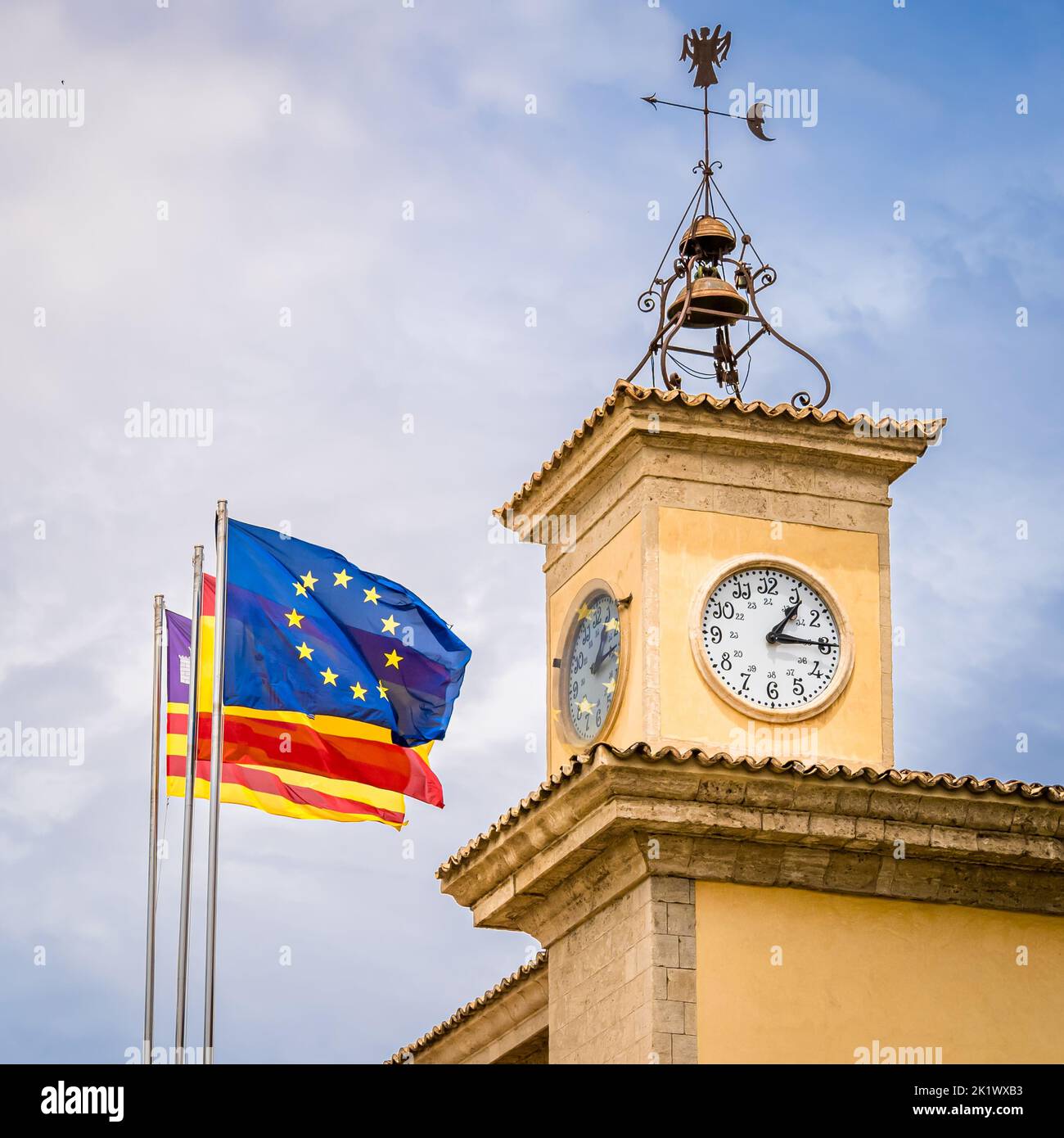 Flags of the European Union, Spain and the Balearic Islands waving in the wind in front of the mediterranean clocktower of the seat of the government. Stock Photo