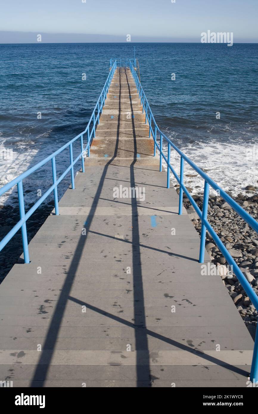 Concrete pontoon with blue metal railing providing bathing access at Santa Cruz's Palmeiras beach Stock Photo
