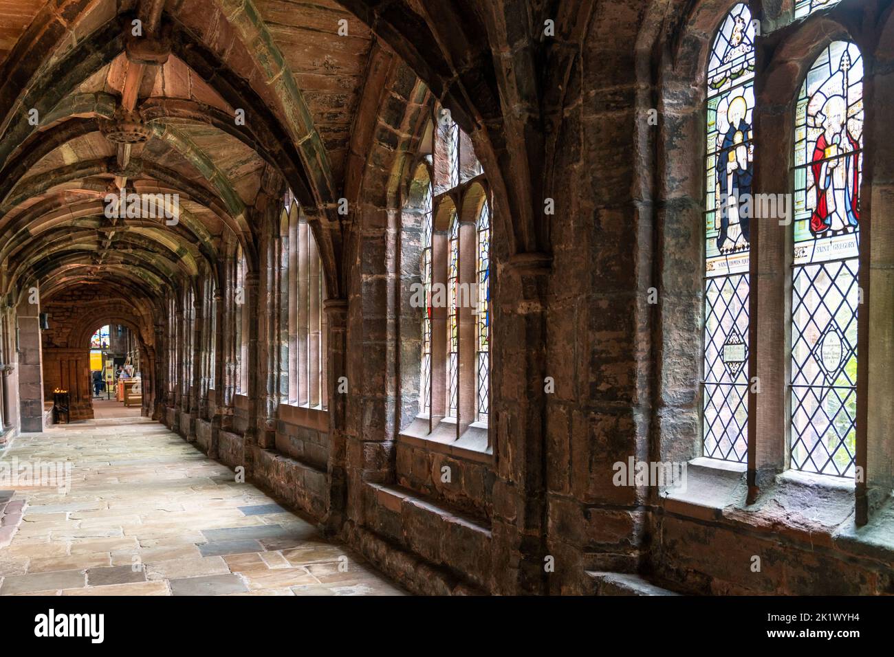 Chester, United Kingdom - 26 August, 2022: view of the cloister hallway in the courtyard of the historic Chester Cathedral with stained glass windows Stock Photo