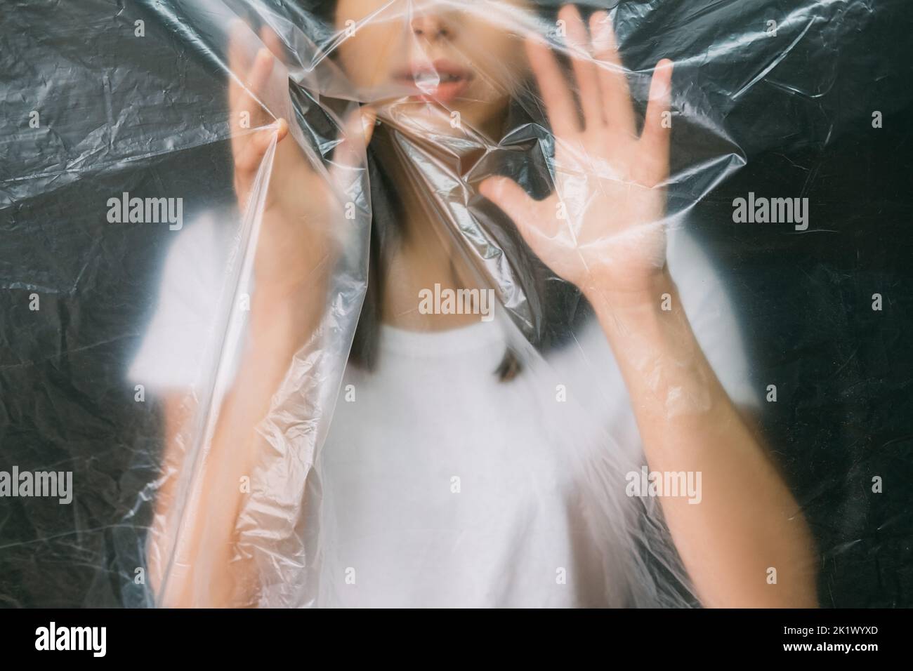 Anxiety attack. Defocused silhouette. Emotional crisis. Fear tense. Cropped portrait of scared paranoid woman trapped behind creased polyethylene film Stock Photo
