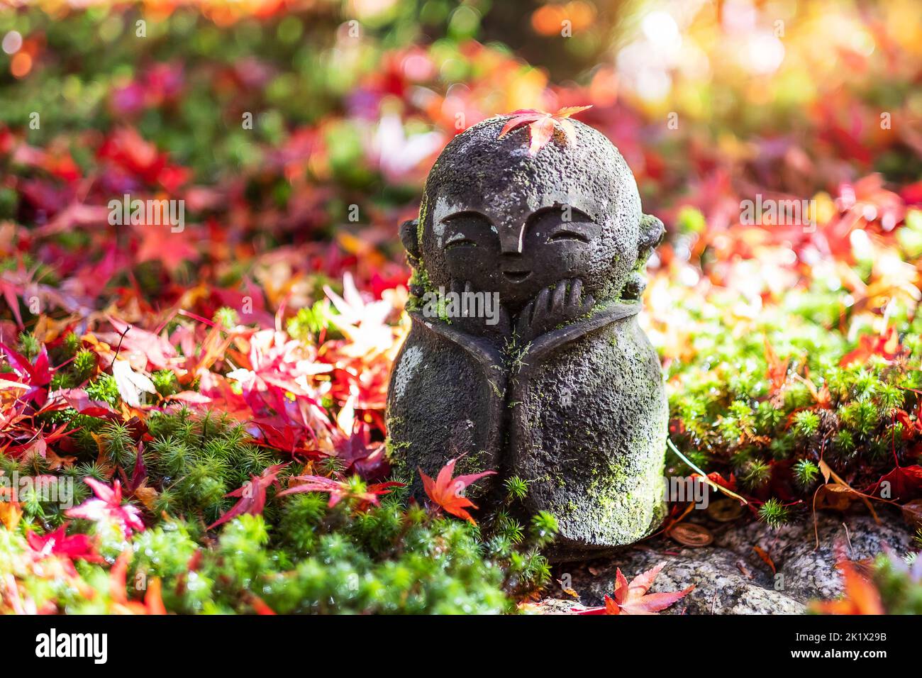 Japanese Jizo sculpture doll with falling Red Maple leaf in Japanese