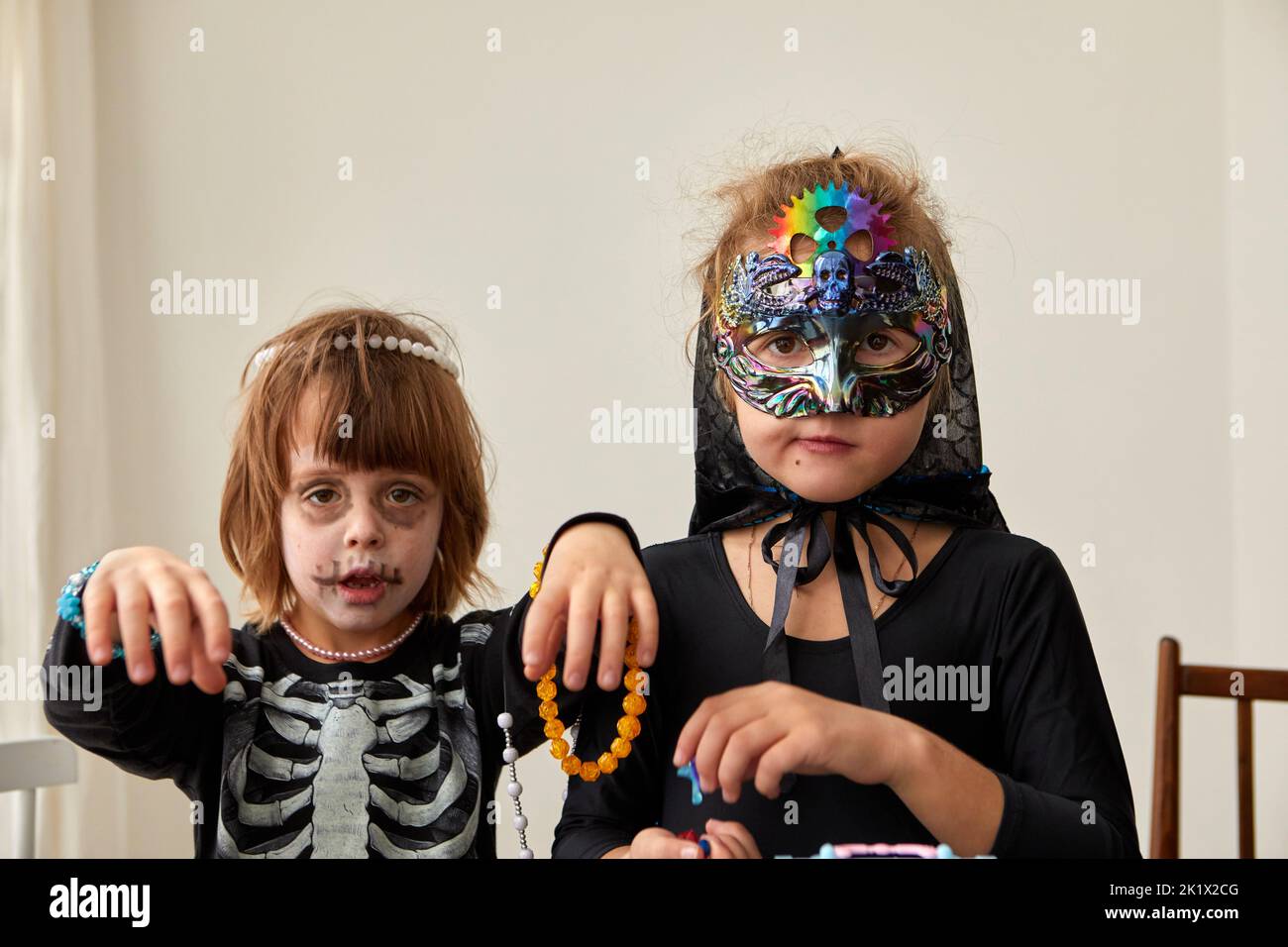 Children trick or treating on Halloween party different costumes decorated in jewelry skeleton and and cyberpunk mask witch white background Stock Photo