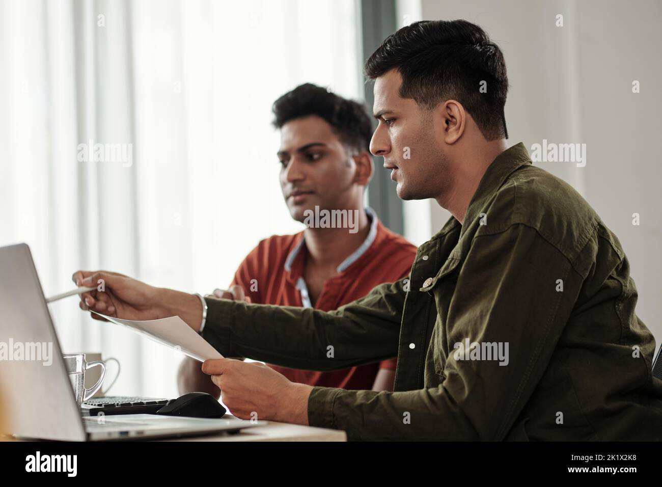 Software developer pointing at computer screen when sharing his idea with colleague Stock Photo