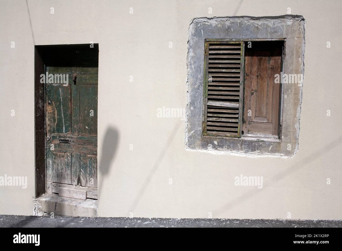 grey wall with flaking green painted door and shutters in Northern Funchal Madeira Stock Photo