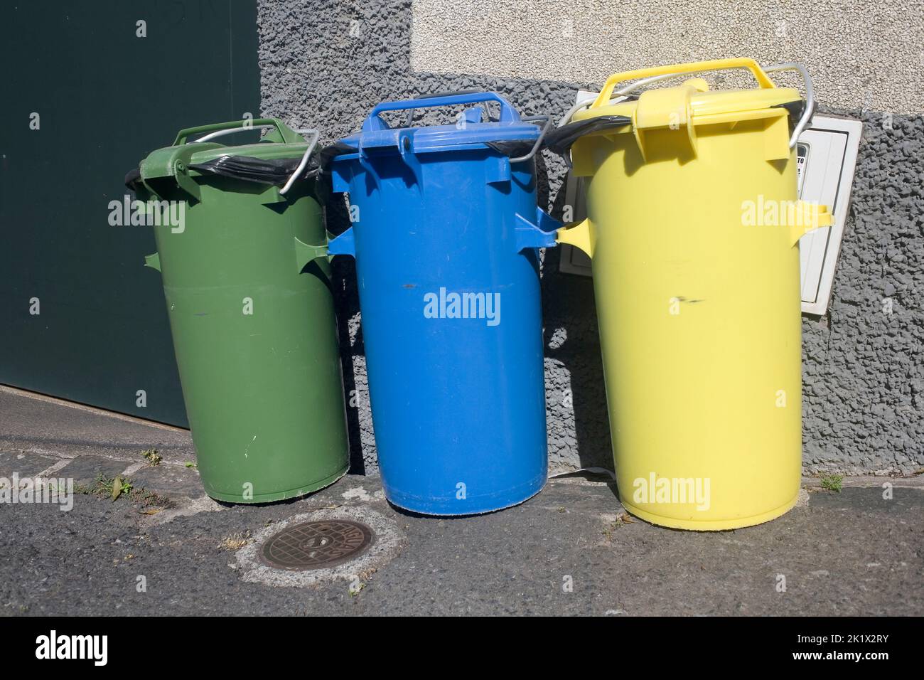 green blue and yellow recycling bins on street in hilly Northern Funchal Madeira Stock Photo