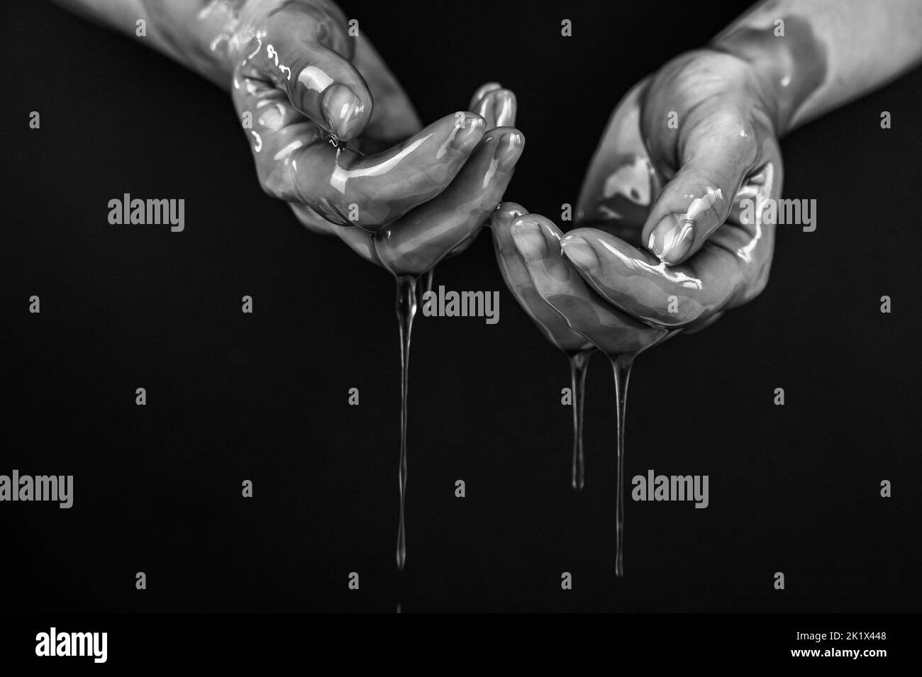 Women's hands in a viscous liquid similar to blood. Black and white