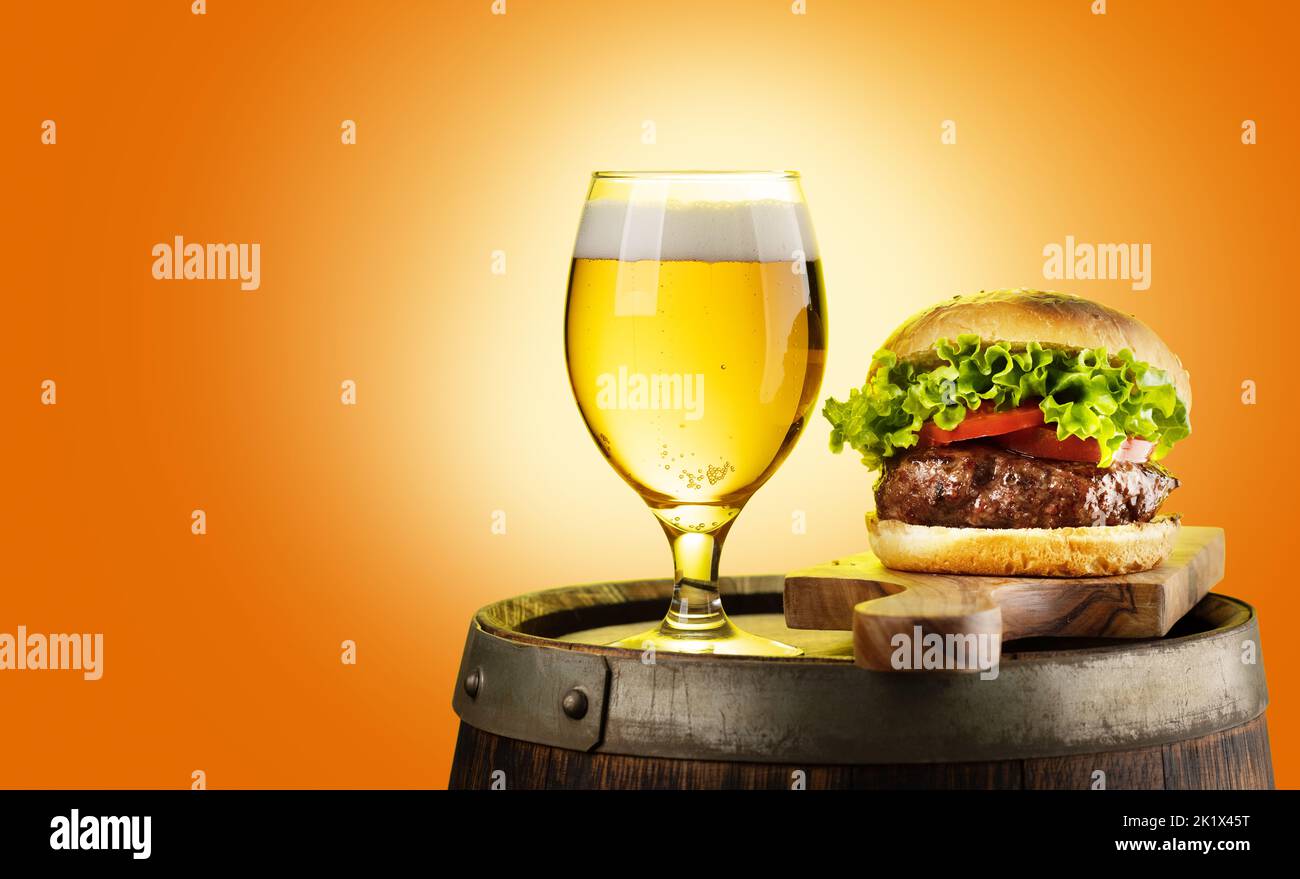 Draft beer glass and hamburger on wooden barrel. With copy space Stock Photo