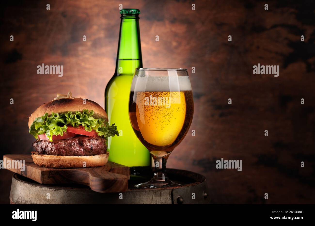 Draft beer glass, bottle and hamburger on wooden barrel. With copy space Stock Photo